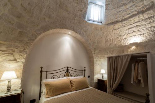 a bedroom with a bed in a stone wall at Trulli Angela in Locorotondo