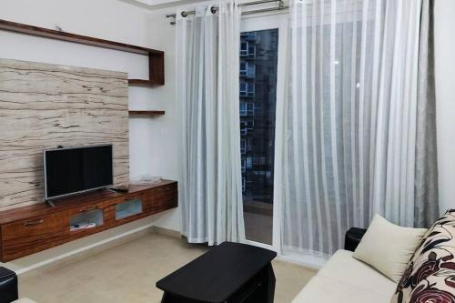 班加羅爾的住宿－SOLACE Premium 2BHK Apartment near Manyata Tech Park And Hebbal，带沙发、电视和窗户的客厅