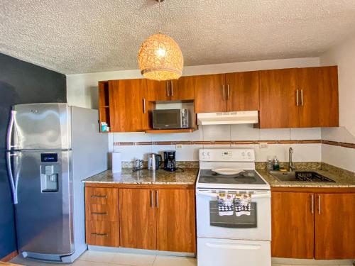 cocina con armarios de madera y nevera blanca en Penthouse Apartment with Spectacular Pool and Mountain Views!, en Jacó