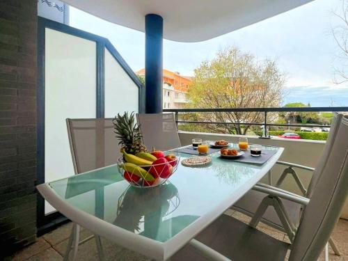 a glass table with a bowl of fruit on a balcony at Appartement T2 rénové proche plage Vieille Chapelle Marseille in Marseille