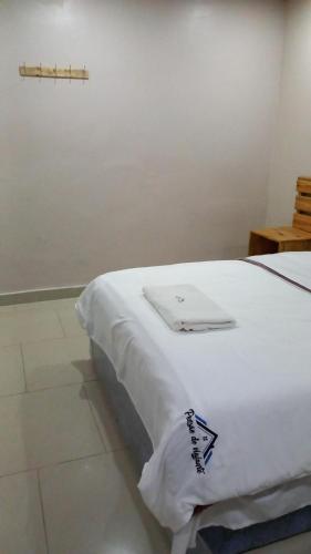 a white bed in a room with a cross on the wall at Pensao do Viajante in Chimoio