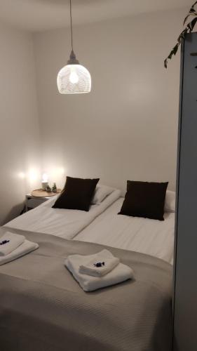 Dos camas en una habitación blanca con toallas. en Hilla Apartments en Rovaniemi