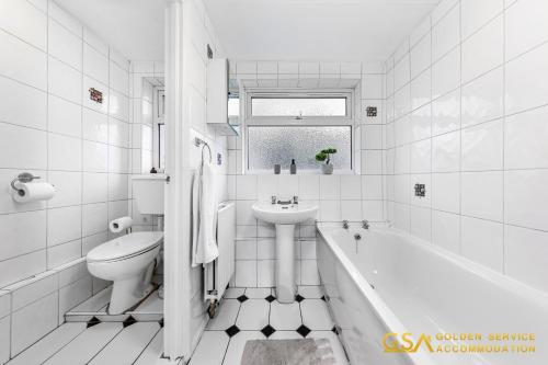 La salle de bains blanche est pourvue d'un lavabo, d'une baignoire et de toilettes. dans l'établissement Stylist and Cosy 3 Bed House Sleeps 7 Free Parking, à Londres