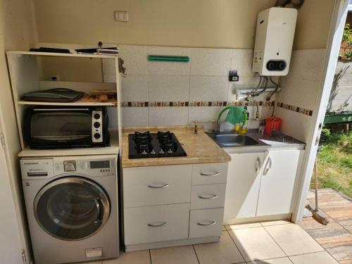uma pequena cozinha com uma máquina de lavar roupa e um micro-ondas em Cómoda casa con estacionamiento privado em Villarrica