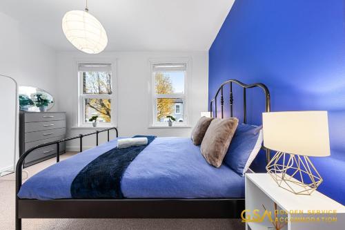 - une chambre bleue dotée d'un lit avec un mur bleu dans l'établissement Stylist and Cosy 3 Bed House Sleeps 7 Free Parking, à Londres
