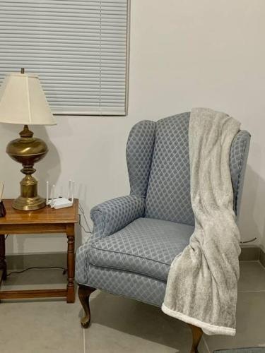 a blanket on a chair next to a table with a lamp at Gabby’s Accesible House in Private area in Mexicali