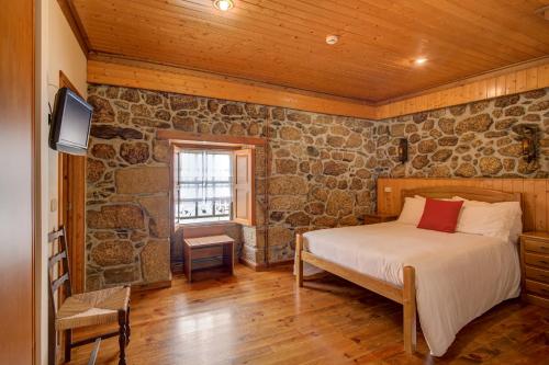 a bedroom with a bed in a stone wall at Casinhas das Tílias in Seia