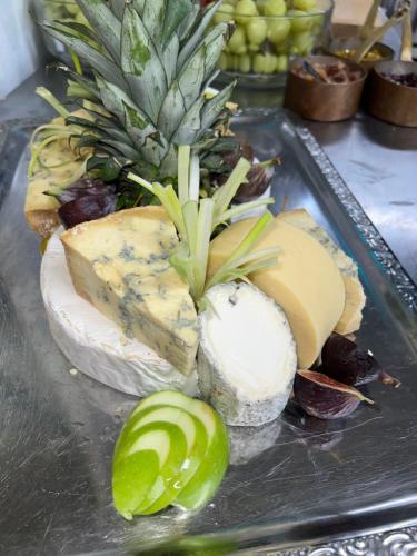 a bunch of cheeses and a pineapple on a table at The Old Manor House Hotel in Keynsham
