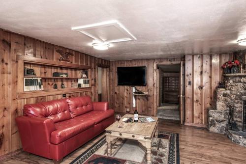 a living room with a red leather couch and a television at Coyote Cabin - Private Hot Tub - Upper Canyon in Ruidoso