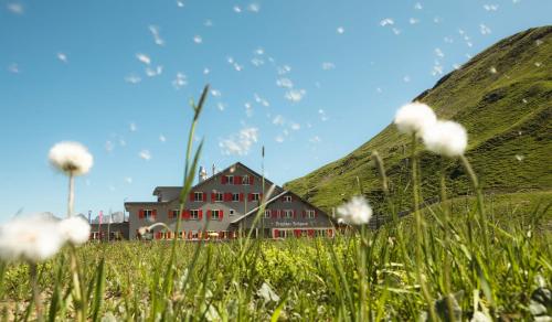 a building in a grassy field next to a mountain at Bärghuis Jochpass - Alpine Hideaway - 2222müM in Engelberg