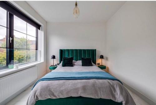 a bedroom with a large bed with a green headboard at Luxury Apartment: city centre, stylish, modern in Chester