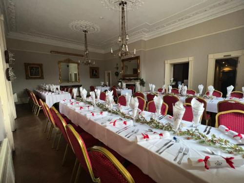 a row of tables in a room with red chairs at The Old Manor House Hotel in Keynsham