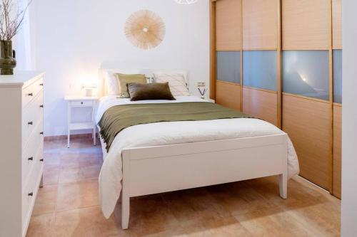 a bedroom with a white bed and a wooden cabinet at Apartamento Catuxa in Malpica