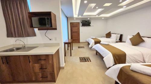 Habitación de hotel con 3 camas y lavamanos en Airos Hotel en Baños