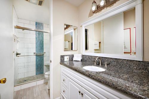 a bathroom with a sink and a mirror and a shower at Oceanfront condo at North Coast Village in Oceanside