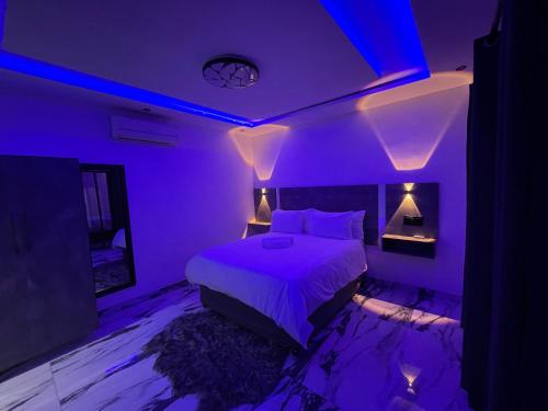 a purple bedroom with a bed and a blue lighting at Rabi’s guesthouse in Mahikeng