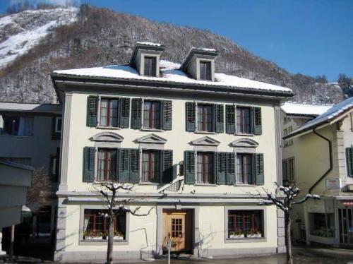 ein weißes Haus mit grünen Fensterläden und einem Berg in der Unterkunft Hotel Rebstock Meiringen in Meiringen