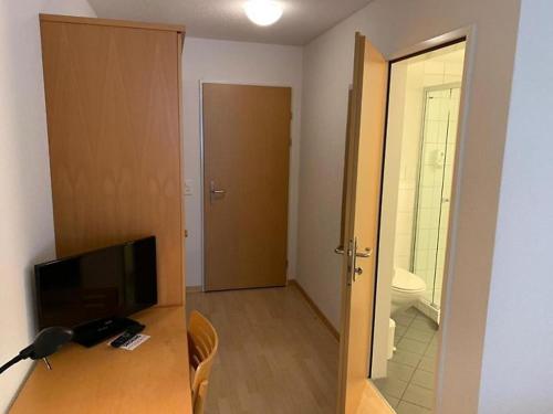 a room with a television and a bathroom with a toilet at Hotel Rebstock Meiringen in Meiringen