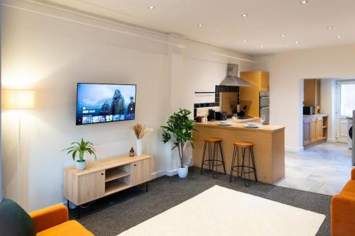 a kitchen and living room with a tv on the wall at Modern cottage WiFi Free Parking in Penwortham