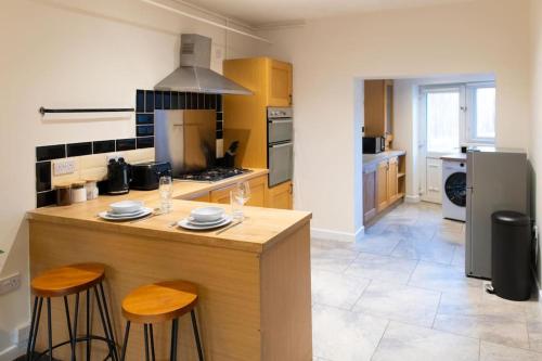 eine Küche mit einer Theke und 2 Hockern in der Unterkunft Modern cottage WiFi Free Parking in Penwortham