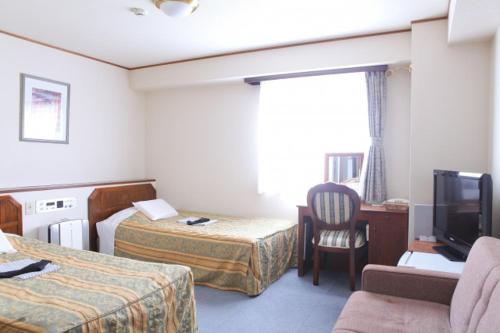 a hotel room with two beds and a television at Terminal Art Inn in Niigata