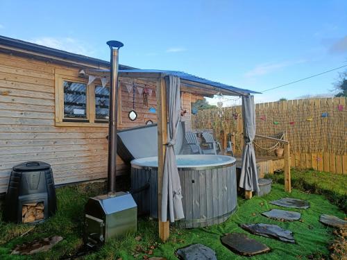 a bath tub in a yard next to a house at Luxury log cabin with wood fired hot tub in Moville