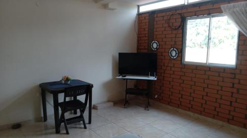 Habitación con escritorio, TV y pared de ladrillo. en Apartaestudio en Tumaco, en Burrero