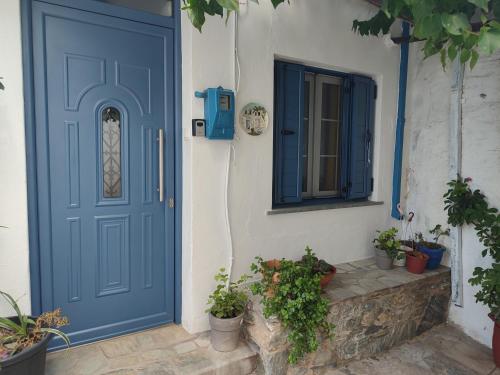 a blue door on a white building with potted plants at KASTRO HOUSE in Skopelos Town