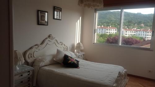 1 dormitorio con cama blanca y ventana en PISO MANCE en Allariz