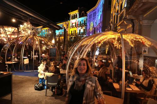 a woman standing in front of a restaurant at night at Hotel America in Locarno