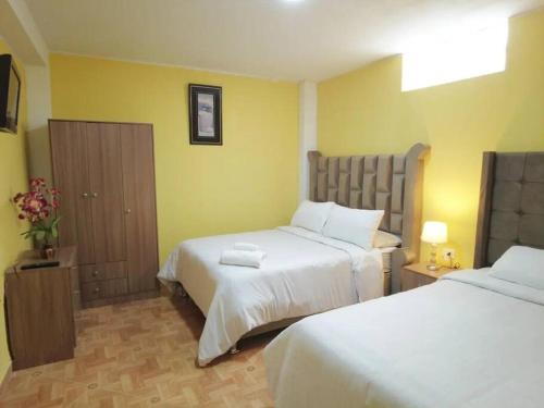 a hotel room with two beds and yellow walls at Departamento Huanca in Huancayo