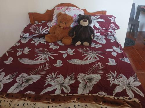 Dois ursinhos de peluche sentados numa cama. em Llave's transient house em Nasugbu