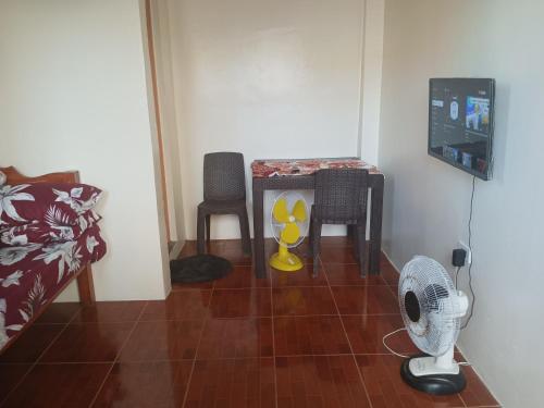 a room with a fan and a table and chairs at Llave's transient house in Nasugbu