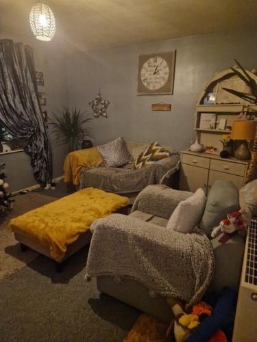 een woonkamer met een bank, een bed en een klok bij Double room in Elloughton