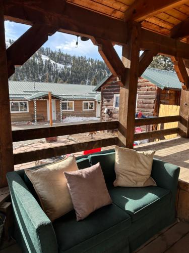 eine grüne Couch auf einer Veranda mit Blick auf eine Hütte in der Unterkunft Deer Lodge in Red River