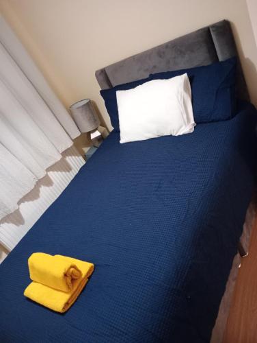 uma cama azul com uma toalha amarela em The Diamond Hearts Apartments em Milton Keynes