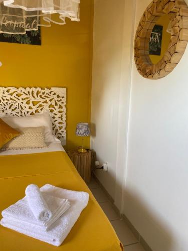 a yellow bedroom with a bed and a mirror at Chez Soul~Etage entier avec vue sur mer in Sainte-Rose