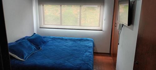 - une chambre avec un lit bleu et une fenêtre dans l'établissement Casa frente Universidad de Manizales 4 habitaciones cerca al centro de la ciudad, à Manizales