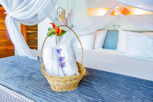 a basket of towels on a bed in a bedroom at RCH LUXURY HOTEL & POOL in Dibulla