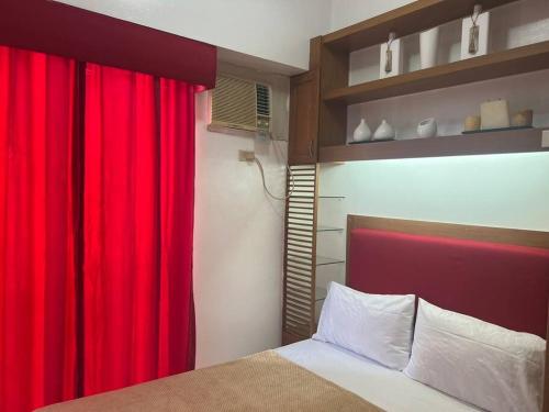 1 dormitorio con cortina roja y cama en Elegant Cozy 2BR Near The Airport, en Manila