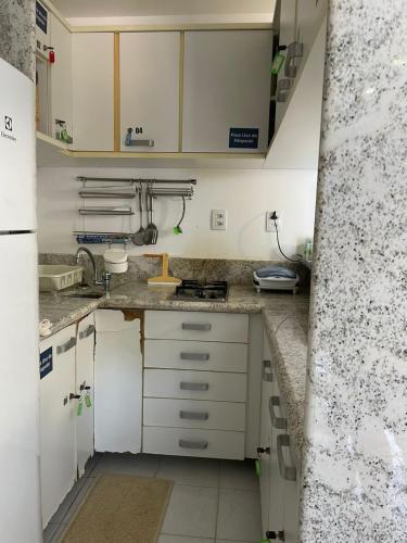 a small kitchen with white cabinets and a sink at Flat Marupiara suítes com a melhor vista de Muro Alto in Porto De Galinhas
