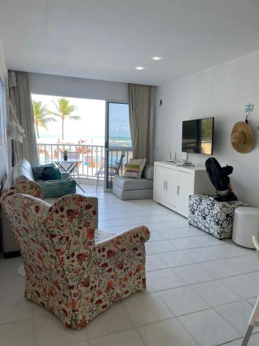 a living room with a couch and a tv and a chair at Flat Marupiara suítes com a melhor vista de Muro Alto in Porto De Galinhas