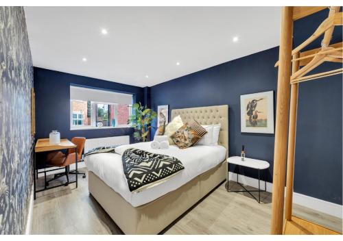 - une chambre avec des murs bleus, un lit et un bureau dans l'établissement Modern Deluxe 3 Bedroom Flat, à Ascot