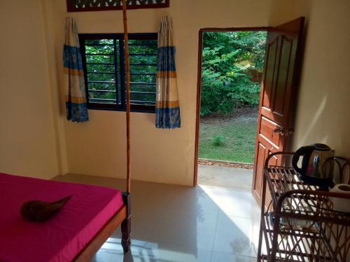 een kamer met een tafel en een deur naar een tuin bij Baloo Guesthouse in Koh Rong Sanloem