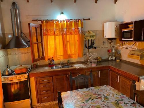 una cocina con cortina naranja y fregadero en CABAÑAS MIS SUEÑOS I, en Merlo