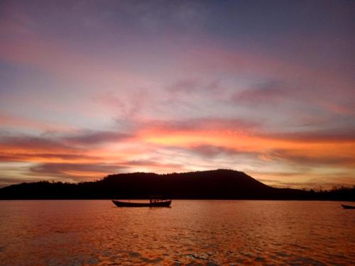a boat sitting on the water at sunset at Baloo Guesthouse in Koh Rong Sanloem