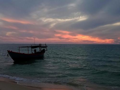 a boat sitting in the water on the beach at Baloo Guesthouse in Koh Rong Sanloem