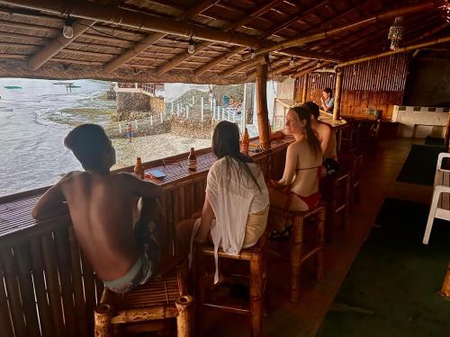 a group of people sitting at a bar looking at the water at Sunnyside Moalboal - 써니사이드 모알보알 게스트 하우스 in Moalboal