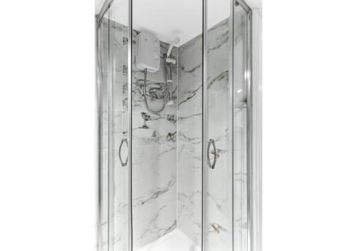 a bathroom with a shower with marble walls at Sleek and Modern Studio with Minimalist Vibe in Chelmsford