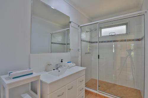 a white bathroom with a shower and a sink at Pacific Sun Bargara in Bargara